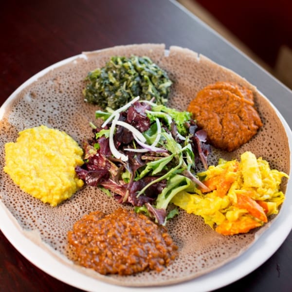 A colorful Ethiopian platter with injera bread, various stews, and a fresh salad.